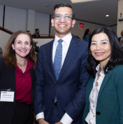 Three people are standing together, smiling, in a professional setting.